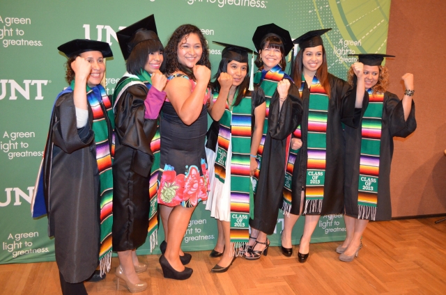 Graduates posing infront of UNT banner