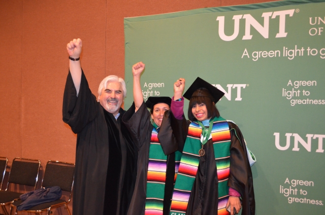 Graduating student posing in front of UNT Banner